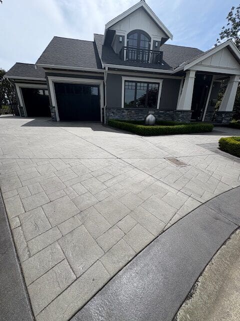 A professionally sealed light grey stamped concrete driveway in Victoria, BC, showcasing a clean satin finish and protective coating on a modern residential property.